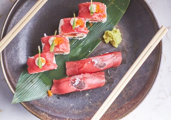 Peças de sushi no prato com uma folha por baixo e dois pauzinhos de cada lado