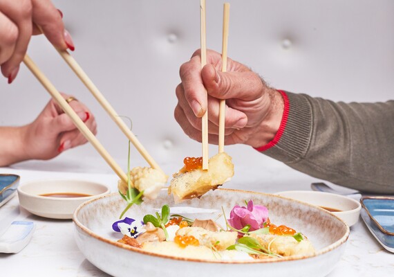 Duas pessoas a servirem-se de sushi no mesmo prato