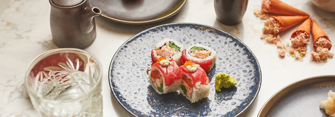Mesa com pratos de sushi, copo de agua e molhos de sushi